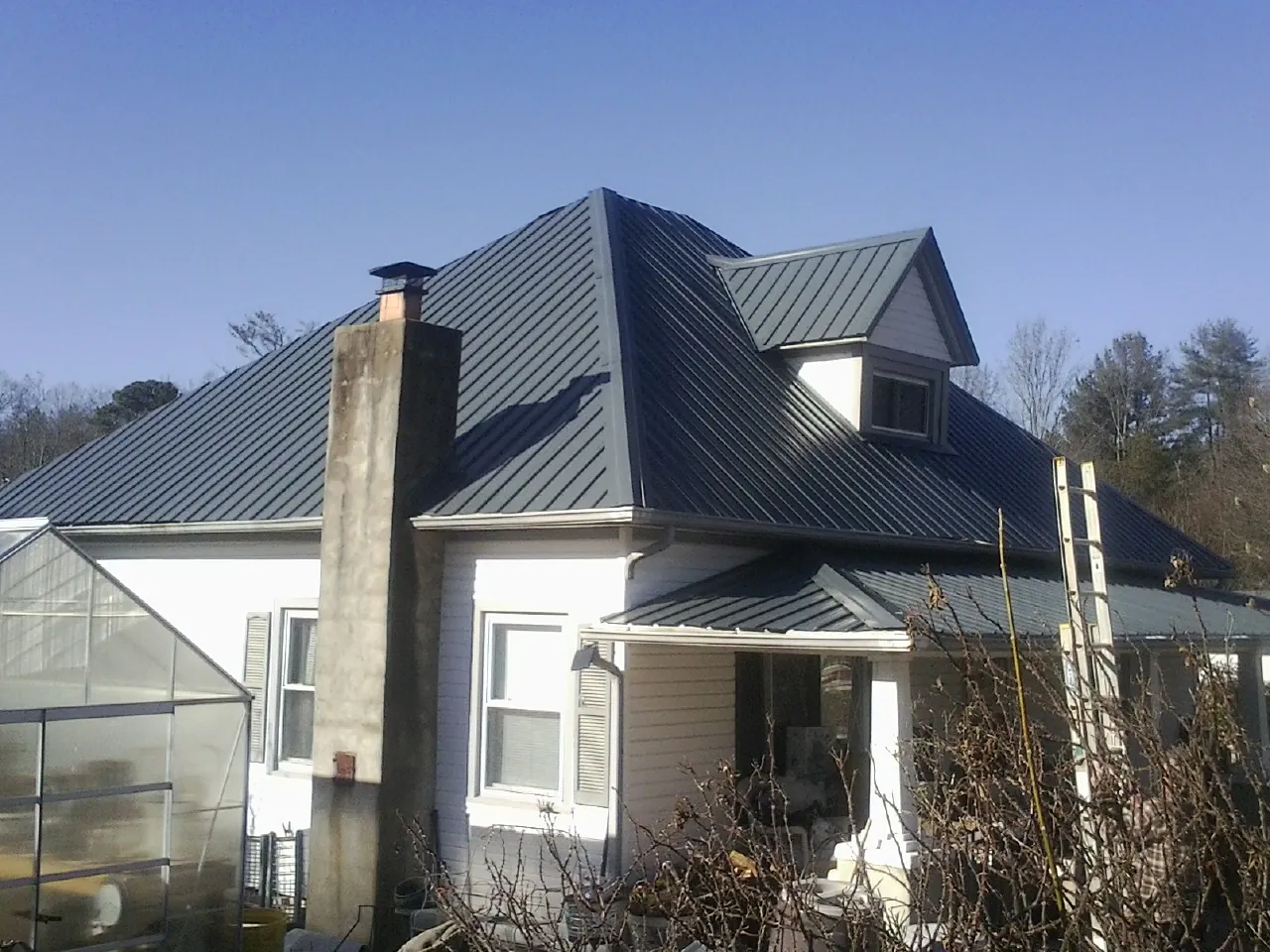Dark blue standing seam metal roof on a white farmhouse with dormer — Slate & Tile Roof Repair by Roofing Brothers in Deep Run