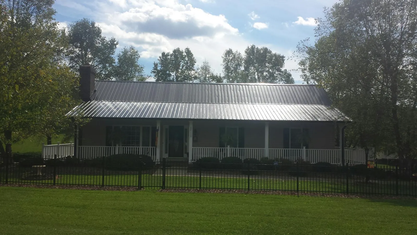 Gray metal roof on a brick ranch with a full width front porch — Gutter Guard Installation work by our crew in Deep Run