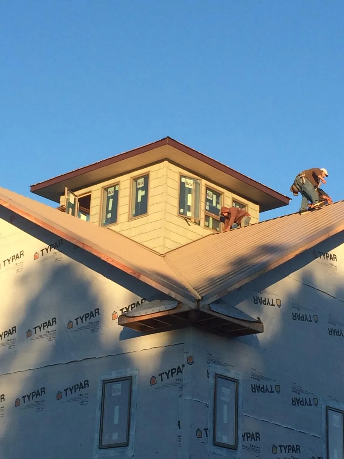 Roofers working around a rooftop cupola on a new metal roof at sunset — Roof Waterproofing in Deep Run by Roofing Brothers